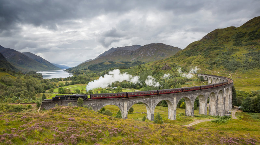 ©VisitBritain/VisitScotland The Jacobite steam train passing over the Glenfinnan Viaduct at the head of Loch Shiel, Lochaber, Highlands of Scotland